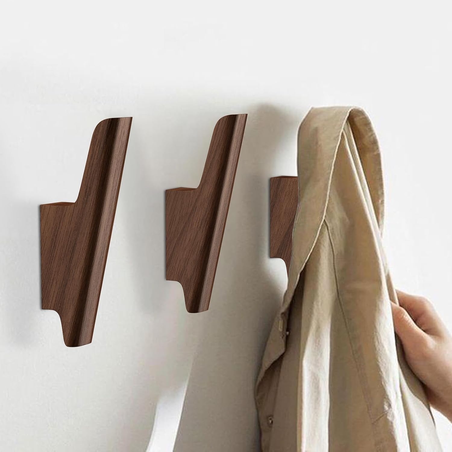 Set of four walnut wood wall-mounted coat hooks with warm earth tone finish, shown installed on white entryway wall — view 2