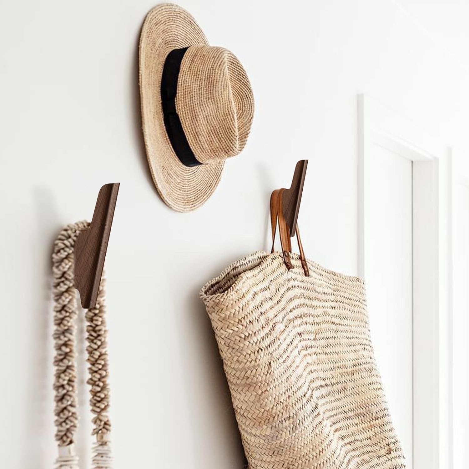 Set of four walnut wood wall-mounted coat hooks with warm earth tone finish, shown installed on white entryway wall — view 4