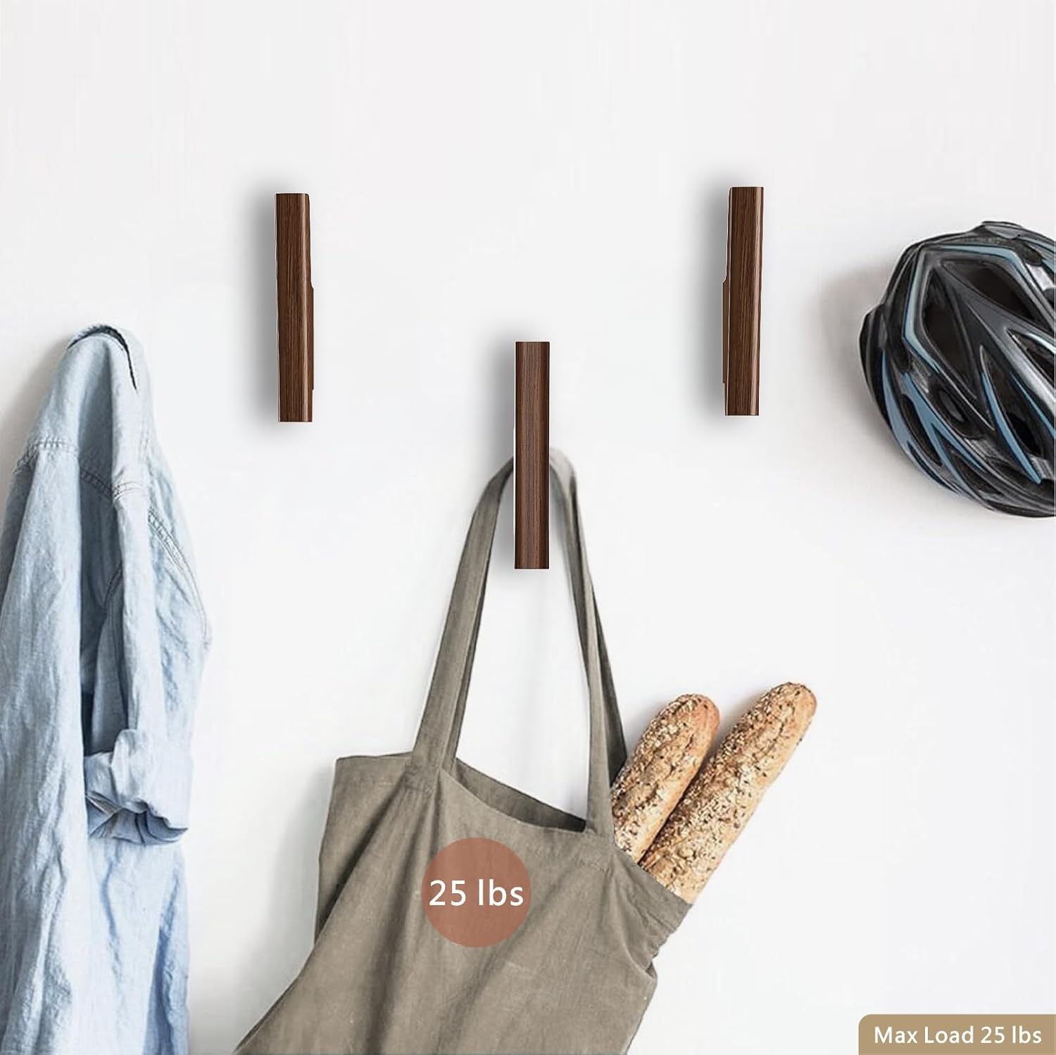 Set of four walnut wood wall-mounted coat hooks with warm earth tone finish, shown installed on white entryway wall — view 3