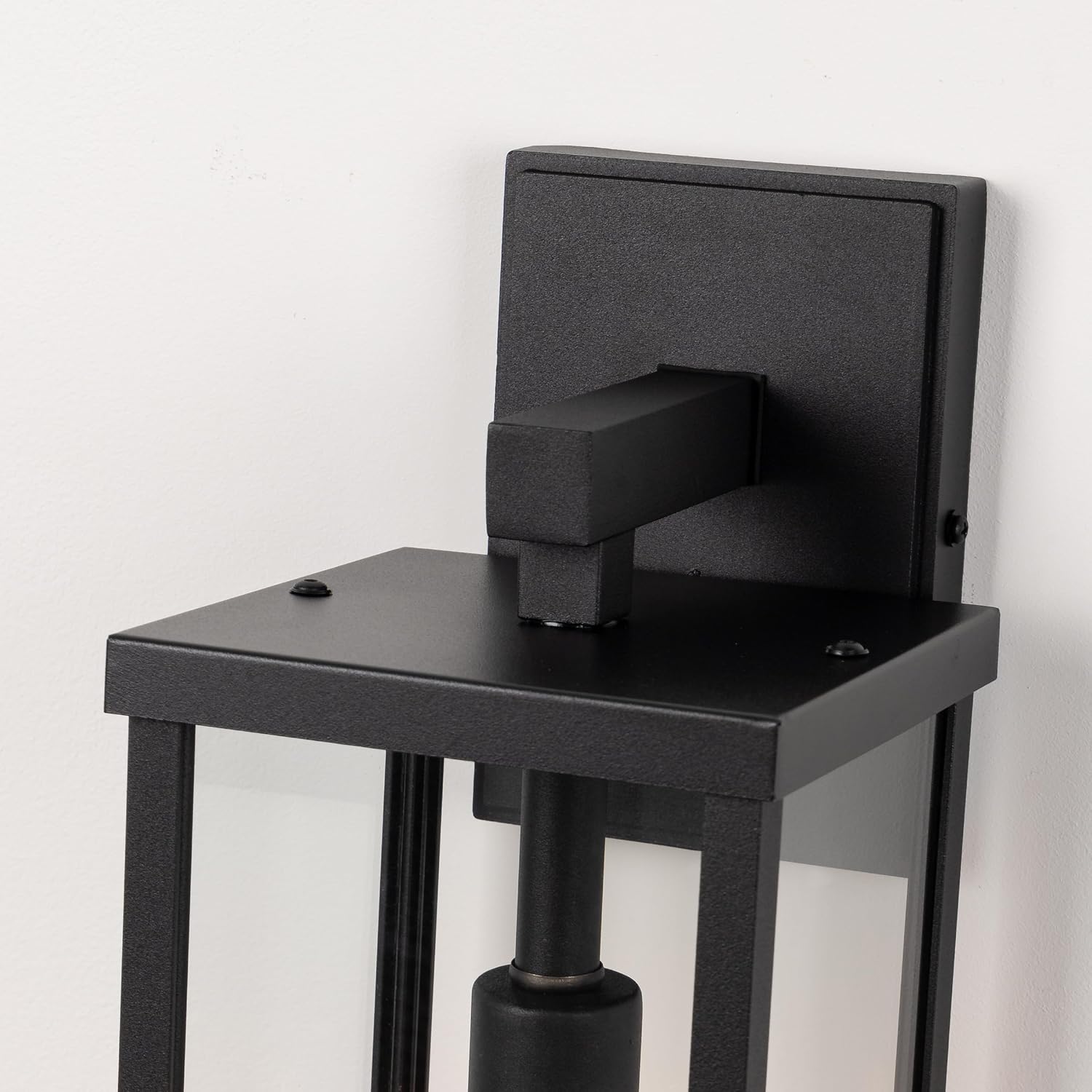 Matte black metal rectangular outdoor wall sconce with clear glass shade, shown mounted on porch exterior — view 3