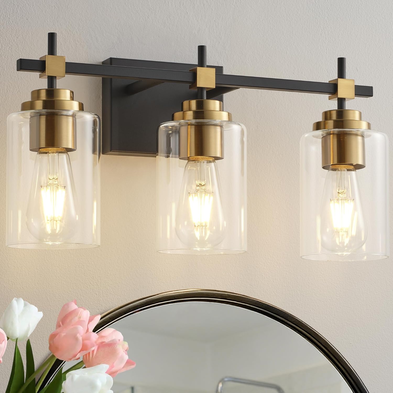 Black metal vanity light fixture with brass accents and clear glass shades for bathroom mirror installation — view 2