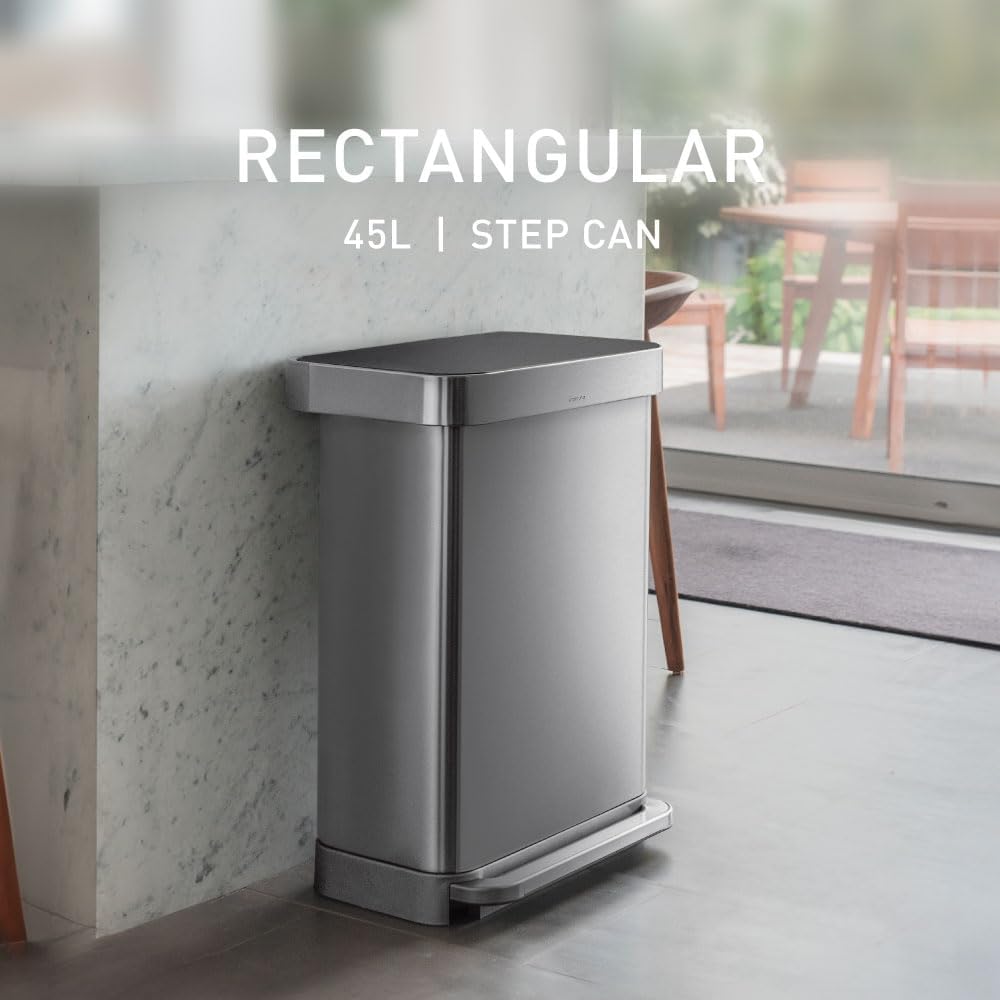 Rectangular brushed stainless steel step trash can with grey plastic lid and pedal mechanism, shown in modern kitchen setting — view 2